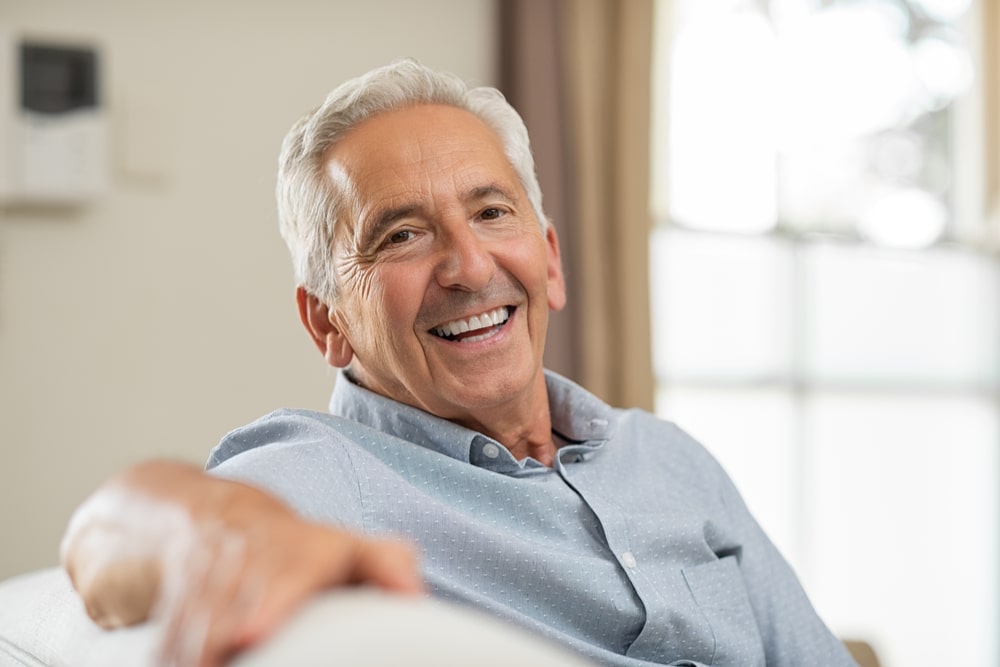 Old citizen smiling sitting sofa