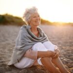 woman wearing shawl sitting relaxed on sand