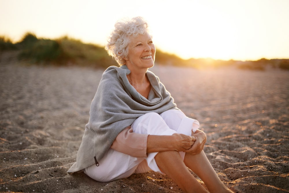 woman wearing shawl sitting relaxed on sand