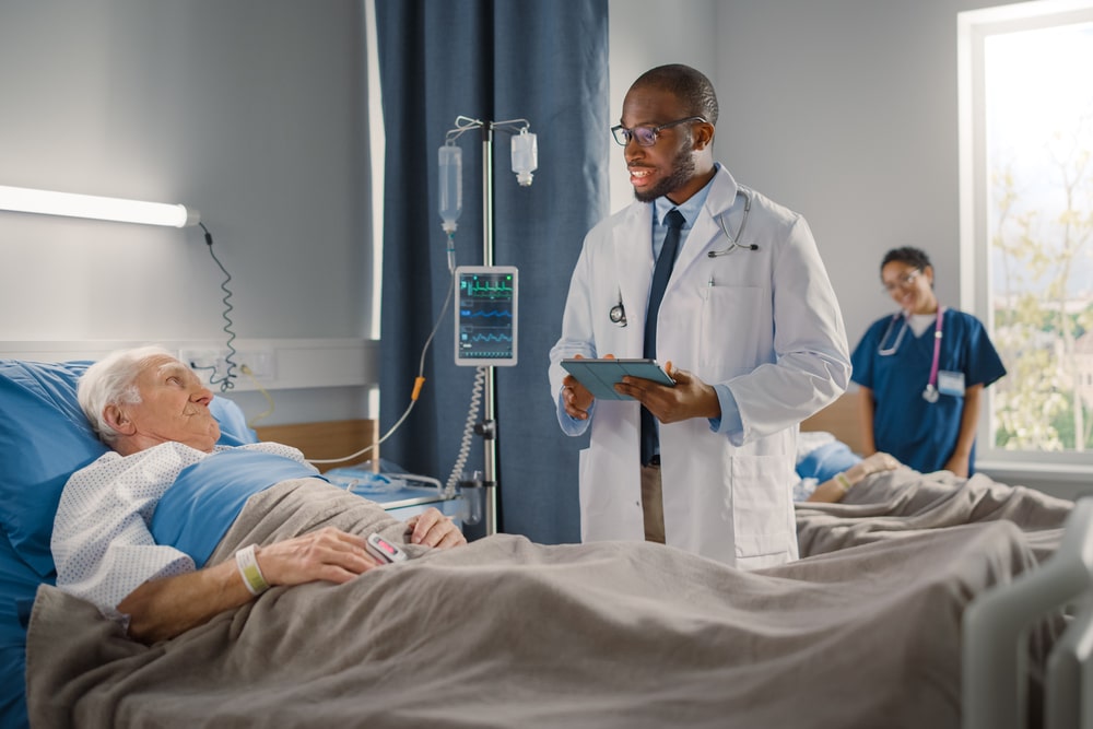Friendly Doctor Talks with Elderly Patient Resting in Bed